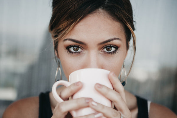 Dunkelhaarige Frau trinkt starken Kaffee aus einem weißen Kaffeebecher