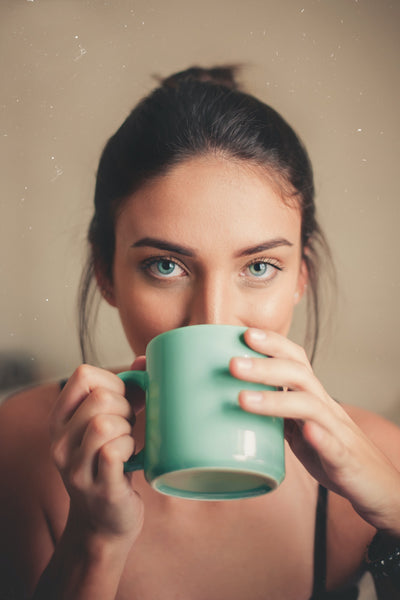 Frau trinkt milden Kaffee aus grünem Kaffeebecher
