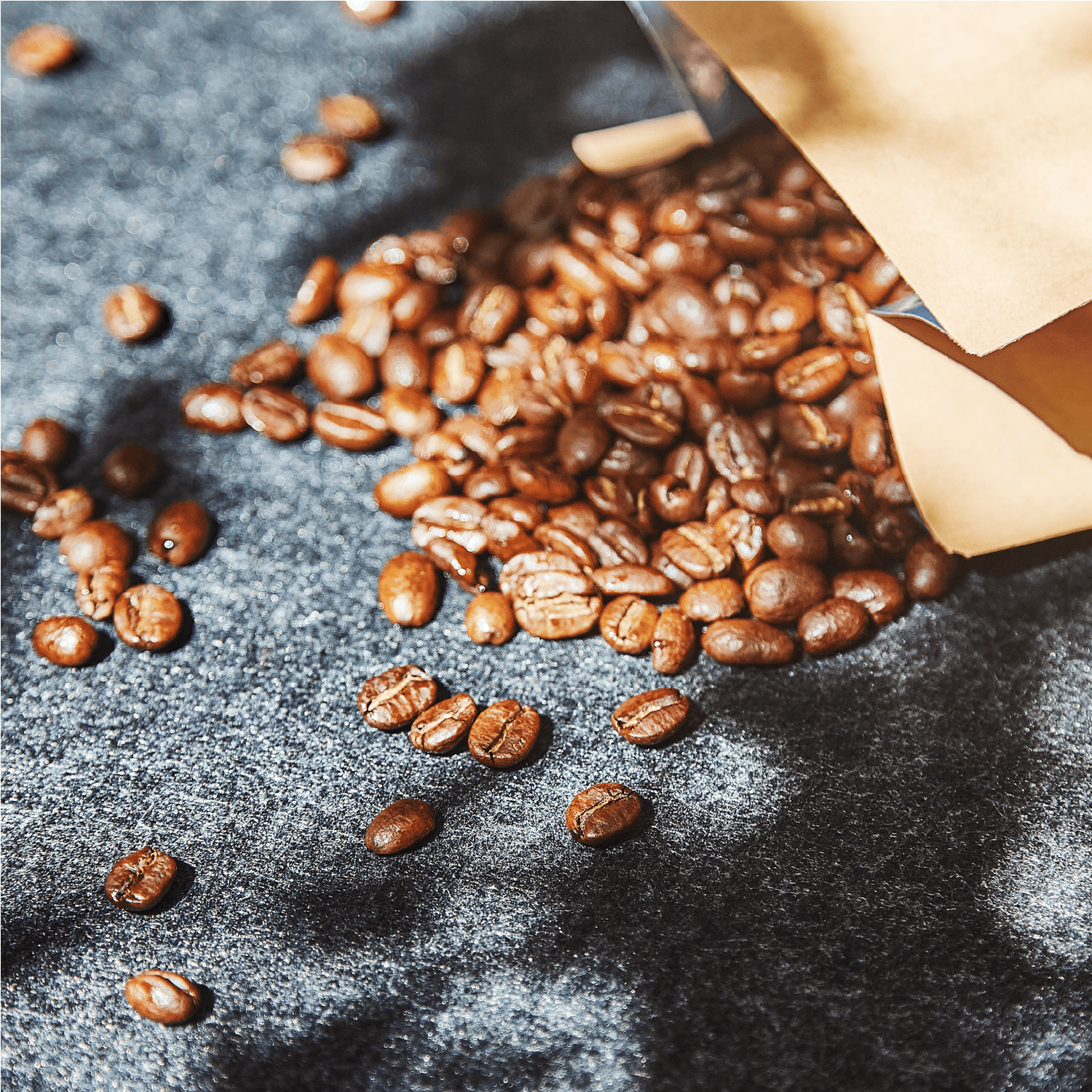 Kaffeebohnen neben einer offenen Kaffeetüte