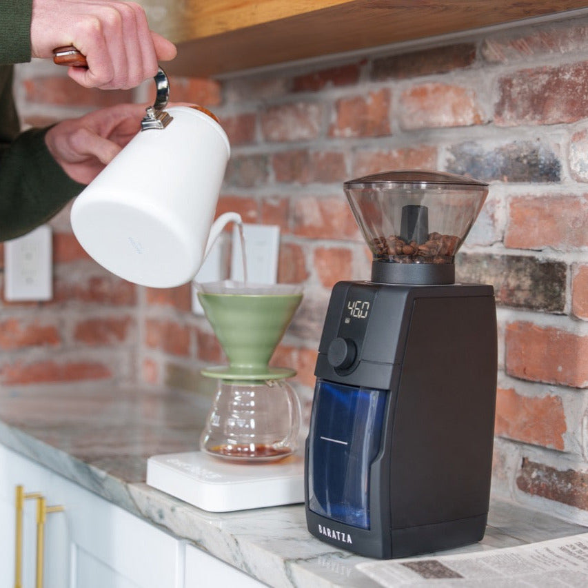 Baratza Encore ESP Pro elektrische Kaffeemühle schwarz, mit transprentem Bohnenbehälter, Seitenansicht der Mühle neben Pour-over Zubereitung