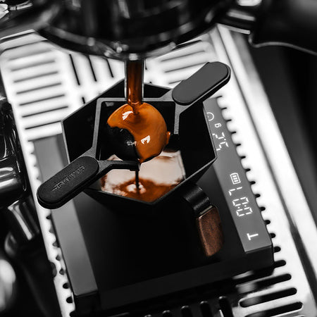 Espresso fließt über den MHW-3BOMBER Cooling Ball in ein schwarzes Gefäß
